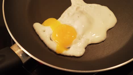Frying-egg-in-a-pan-and-piercing-yolk-with-a-fork