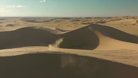 Aerial-of-desert-sand-dunes-with-motocross-riders-and-a-man-running