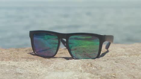 Black-wayfarer-style-sun-glasses-by-seaside-REAL-TIME,-SHALLOW-DOF