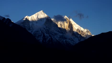 Lapso-De-Tiempo-Desde-El-Amanecer-Hasta-El-Atardecer-De-Las-Nubes-Rodando-Y-Fluyendo-Sobre-Los-Picos-De-La-Cordillera-Del-Himalaya,-Cinturón-Superior-De-Hilayan,-Uttarakhand,-India-Con-Un-Hermoso-Fondo-De-Cielo-Azul
