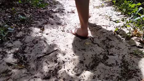 Following-a-woman's-feet-on-beach-sand-walking-through-a-forest-in-slow-motion