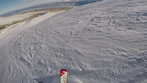 Perspektive-Eines-Skifahrers,-Der-Einen-Hang-Hinunterfährt,-Mit-Bergen-Und-Einem-See-In-Der-Ferne