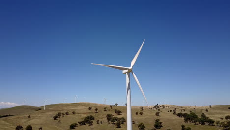 Pan-around-wind-turbine-to-reveal-windfarm-on-barren-breezy-hillside