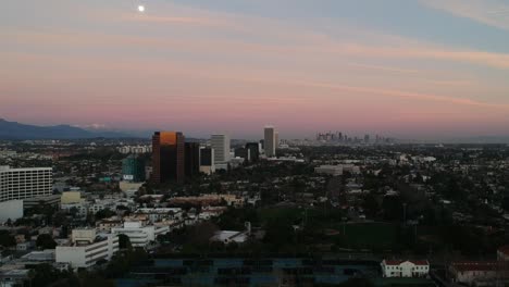 Downtown-Los-Angeles-buildings-in-the-horizon-with-snow-capped-mountains-on-an-colorful,-early-evening