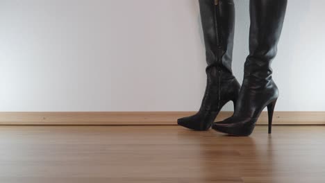 female-model-in-high-heeled-black-platform-leather-boots-stamps-furiously-on-the-floor-to-destroy-something-invisible