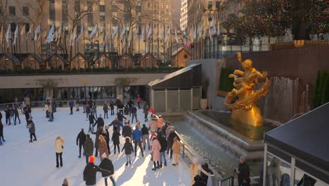 Rockefeller-Center-Christmas-Tree,-Prometheus-Statue-On-Fountain-And-People-Skating-At-The-Ice-Rink-During-Sunset-In-NYC,-USA