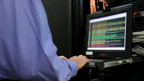 Male-engineer-with-blue-shirt-works-on-computer-in-a-data-center,-server-room
