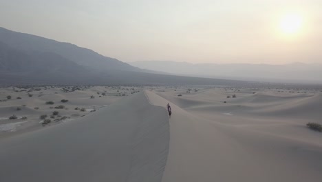 Aerial-Drone-Shot-of-Group-of-People-Walking-on-Sand-Dune-in-Death-Valley