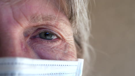 Close-up-of-an-old-woman-face-and-eye-with-a-medical-patient-mask-to-prevent-spreading-a-disease-or-getting-sick