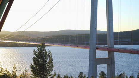 Pan-view-of-a-car-driving-over-a-bridge,-at-a-sunny-evening,-at-Hoga-Kusten,-Vasternorrland,-Sweden