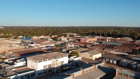 Un-Dron-Tirado-Hacia-Atrás-De-Edificios-Industriales-En-Las-Afueras-De-Bulawayo,-Zimbabwe-Al-Atardecer