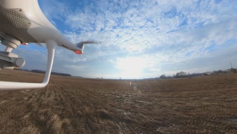 Close-up-Side-View-of-Dji-Phantom-4-Quadcopter-Drone-Flying-Forward-Over-Fields