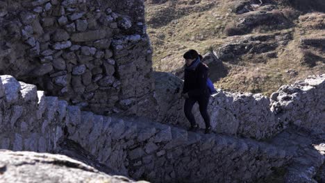A-girl-in-winter-clothes-climbing-up-rocky-stairs-from-an-ancient-fort