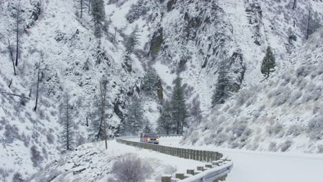 Un-Camión-Tirando-De-Un-Remolque-Pasa-Por-Una-Carretera-De-Invierno-Cubierta-De-Nieve-En-Las-Montañas
