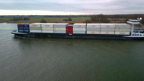 Aerial-view-of-slow-moving-and-heavy-loaded-containership-on-the-dutch-canal-"Oude-Maas"-in-Zwijndrecht,-The-Netherlands