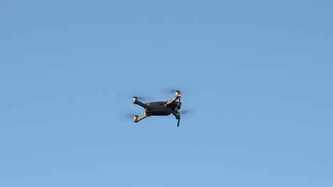 Drone-hovering-in-mid-air-as-another-drone-flys-close-by-at-high-speed