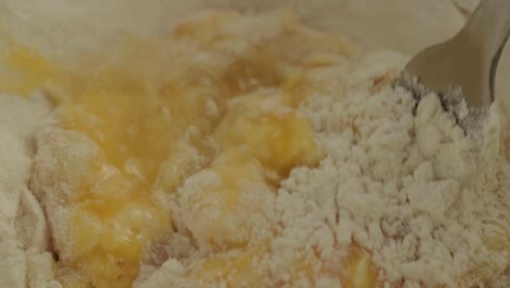 Macro-shot-mixing-eggs-into-flour-with-fork