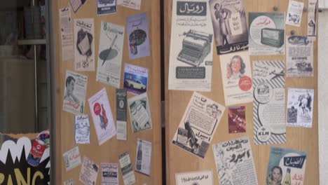 A-hip-novelty-cafe-and-store-in-Al-Qaysariya-Souq-in-Muharraq,-Bahrain-with-old-newspaper-ads-stuck-on-its-doors