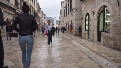 Dolly-De-Una-Joven-Pareja-De-Turistas-Caminando-Por-Stradun,-La-Calle-Principal-De-Dubrovnik