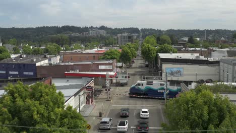 Cars-Stopped-On-The-Street-As-A-Train-Passes-By-On-The-Railway-In-Puyallup,-Washington---aerial-slowmo