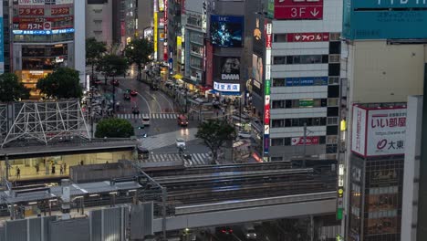 High-Above-Timelapse-out-towards-Shibuya-Crossing-and-skyscrapers-on-rainy-evening-in-Tokyo,-Japan---Tilt-UP