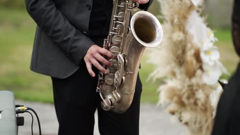 Close-up-Saxophonis-in-black-suit-playing-golden-saxophone-at-wedding