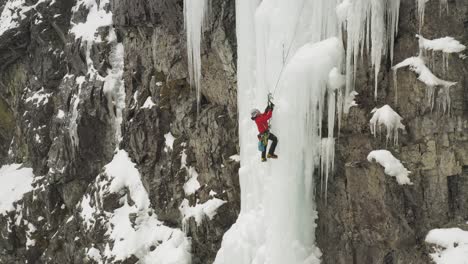 Lone-ice-climber-shakes-off-ice-from-axe-climbing-cascade-Maineline,-Mount-Kineo