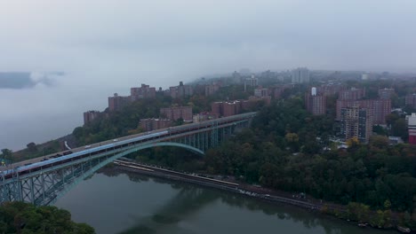 Aerial-back-away-from-the-Henry-Hudson-Bridge-with-low-fog-over-the-river-in-the-early-morning