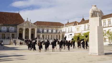 Studenten-Der-Universität-Coimbra-Werfen-Traditionelle-Umhänge-In-Die-Luft,-Portugal