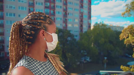 Pretty-Young-African-American-Woman-With-Braids-and-a-Face-Mask-Standing-Outside-During-Covid-19-Virus-Outbreak,-Full-Frame