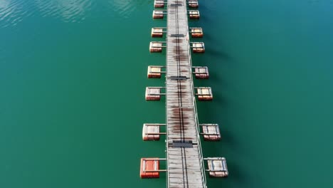 Forward-moving-aerial-view-of-floating-pontoon-bridge-in-the-middle-of-a-peaceful-turquoise-lake-called-Lake-Okutama-in-Tokyo