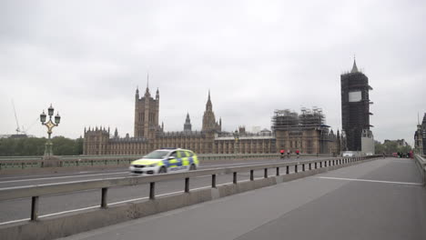 A-police-car-drives-past-the-Houses-of-Parliament-as-it-crosses-a-near-deserted-Westminster-Bridge-during-the-Coronavirus-outbreak