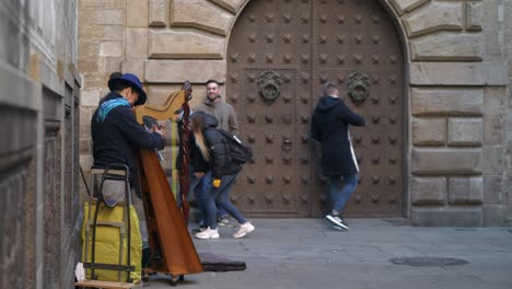 Tourists-stopping-to-listen-to-classical-wooden-harp-street-performer-in-medieval-Barcelona-street