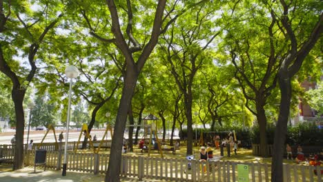 Hermoso-Día-Soleado-En-El-Parque-Del-Barrio-De-Sant-Marti-Con-Niños-Usando-El-Patio-De-Recreo