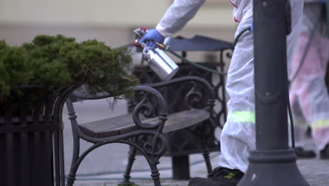 Firefighter-spraying-public-bench-with-disinfectant-on-city-main-square