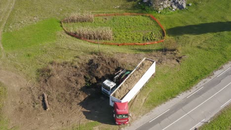 Aerial-wide-top-shot-of-a-man-arranging-his-truck's-load-full-of-woodchips