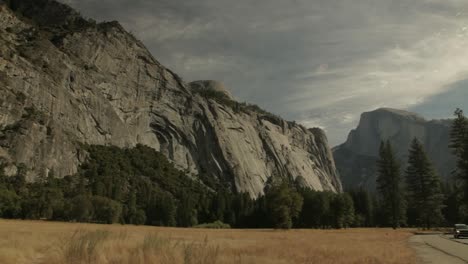 Slow-Pan-Right-Across-Grassland-With-View-Of-Granite-Cliffs-At-Yosemite