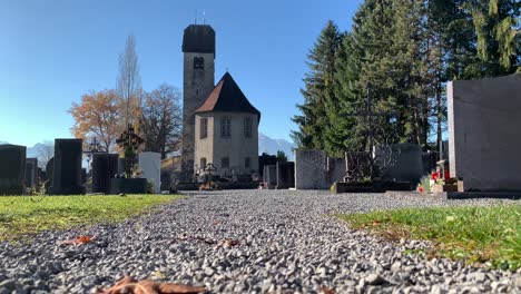 Eine-Alte-St.-Michael-Kirche-Liegt-Bei-Tageslicht-Mit-Herbstblättern-Und-Blauem-Himmel-Mitten-Auf-Dem-Friedhof