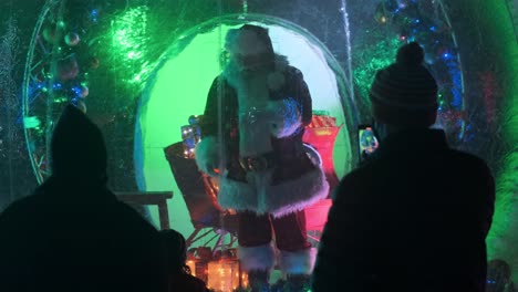 Santa-Claus-socially-distanced-in-plastic-bubble-performs-for-group-of-people