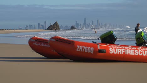 Inflatable-Rescue-Boats-On-The-Beach---Surfers-With-Surfboard-Walking-Towards-The-Ocean-To-Surf---Currumbin,-Gold-Coast,-Queensland,-Australia