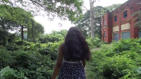 Beautiful-young-girl-walk-towards-scary-abandoned-house-alone,-slow-motion,-smooth-dolly-shot
