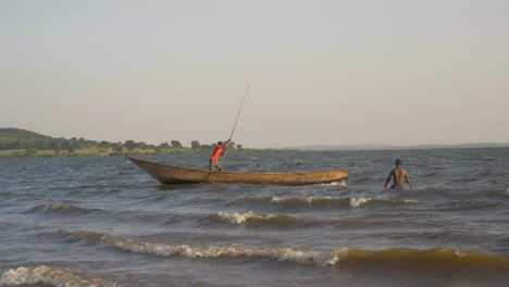 Wide-shot-of-a-windy-Lake-Victoria-with-swimmers-and-fishermen-in-traditional-boats-among-the-waves