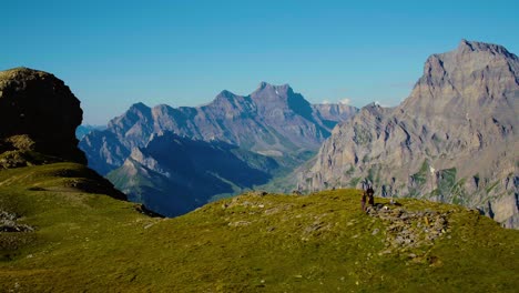 Overflying-hikers-on-mountain-pass-with-high-rocky-peaks-in-the-background-Col-des-Perris-Blancs---the-Alps,-Switzerland