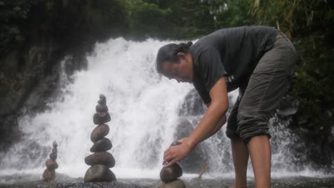 Men-building-cairns-rock-sculpture-in-fast-flowing-river-for-relaxation
