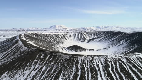 Toma-Aérea-Del-Volcán-Hverfjall-En-Islandia-Y-Las-Montañas-Circundantes-Cubiertas-De-Nieve