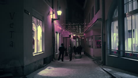 Tourists-walking-on-narrow-street-in-Old-Town-with-neon-decorations-zoom-in