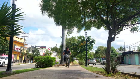 Mann,-Der-In-Mexiko-Auf-Einer-Belebten-Straße-Mit-Dem-Fahrrad-Mitten-Auf-Dem-Mittelstreifen-Fährt,-Während-Auf-Beiden-Seiten-Autos-Vorbeifahren