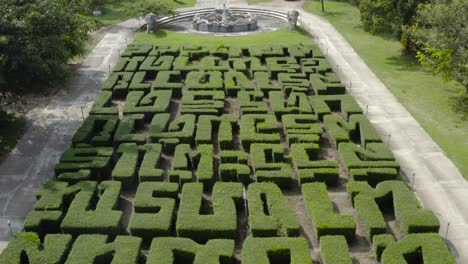 A-beautiful-drone-shot-rising-from-bushes-spelling-phrases-in-thai,-to-the-stairs-that-lead-to-a-temple