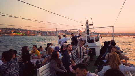 Slow-motion:Unidentfied-people-have-Istanbul-boat-tour-with-view-of-bosphorus-and-New-Mosque-at-sunset-in-istanbul,Turkey