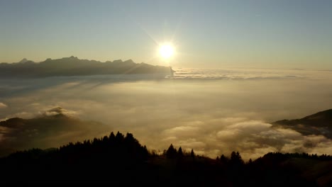 Aerial-orbit-around-hill-surrounded-by-sea-of-clouds-at-sunset,-Switzerland